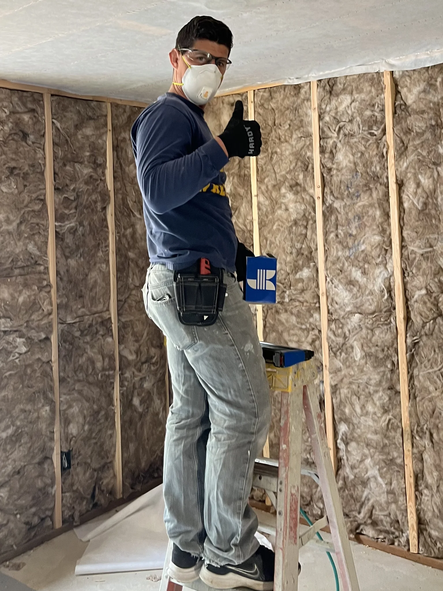 Cody Burdett installing insulation in a basement with a netted ceiling and insulated walls